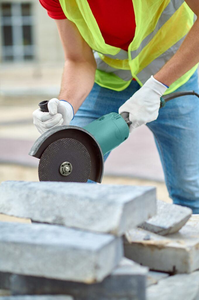 Construction worker cutting concrete blocks with an electric circular saw at an outdoor site