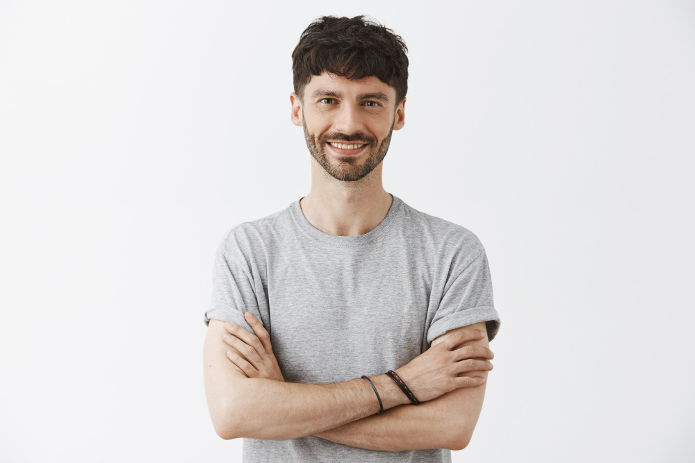 Smiling man with crossed arms wearing a gray t-shirt on a white background