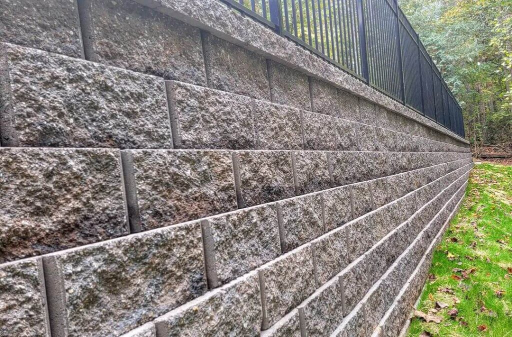Concrete retaining wall built with interlocking blocks next to a grassy area