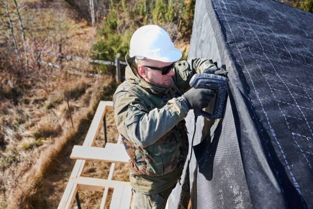Construction worker installing waterproof membrane on a wooden structure